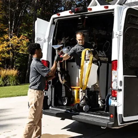 Two Green Clean team members getting equipment from a truck